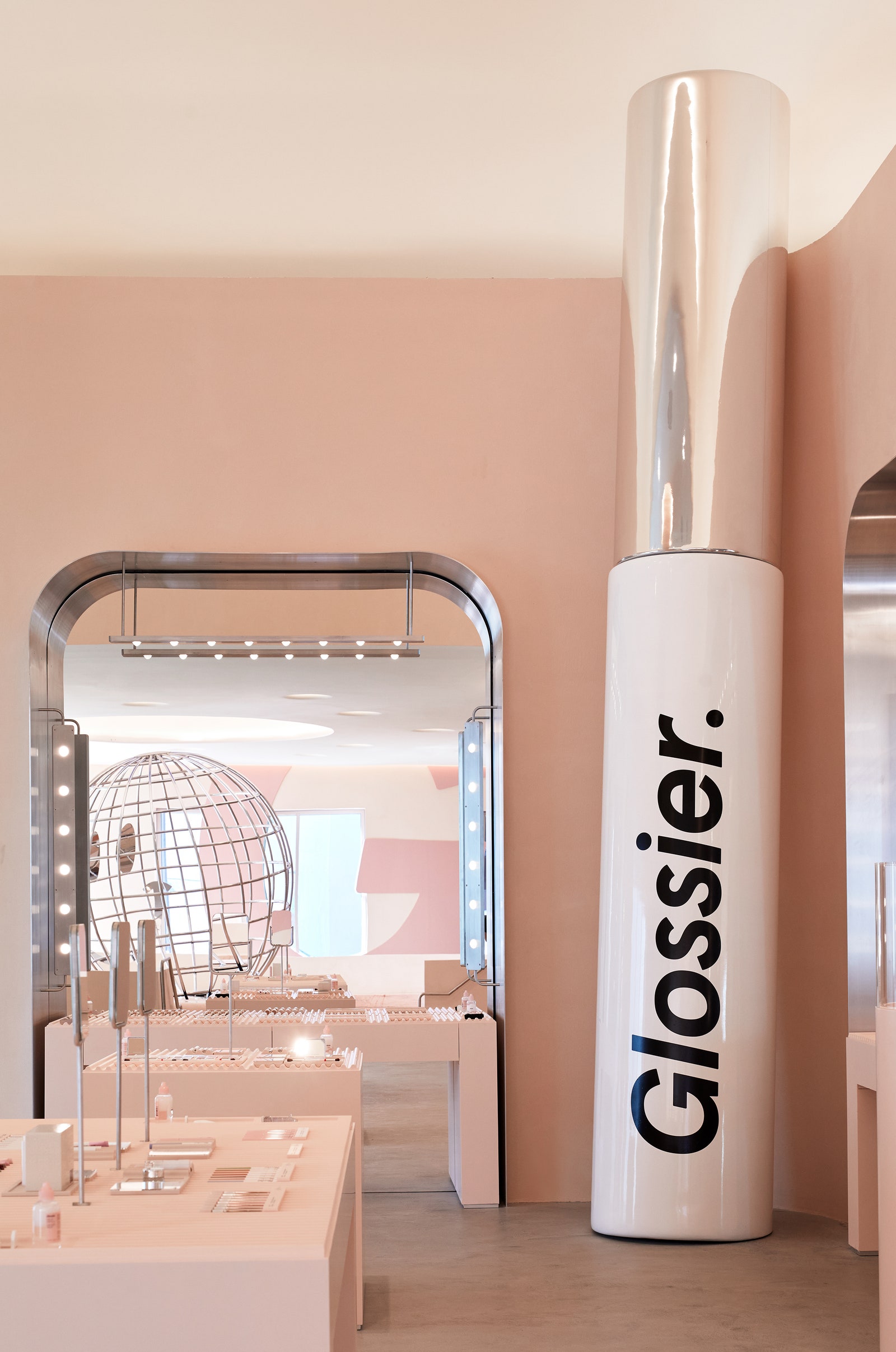 Una gran cantidad de accesorios, como el tubo Glossier Lip Gloss de 20 pies de altura, resaltan la deslumbrante calidad del país de las maravillas del diseño de la tienda.