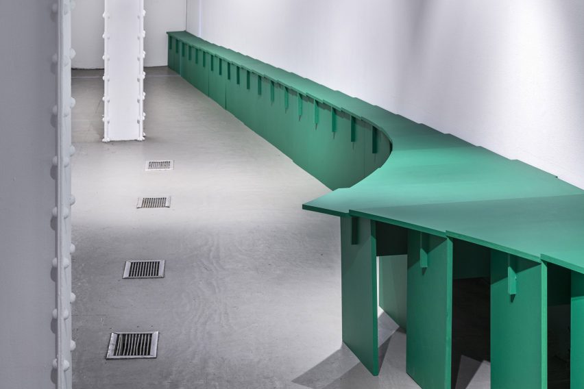 Una serie de mesas verdes curvas en el escaparate de arte y arquitectura.