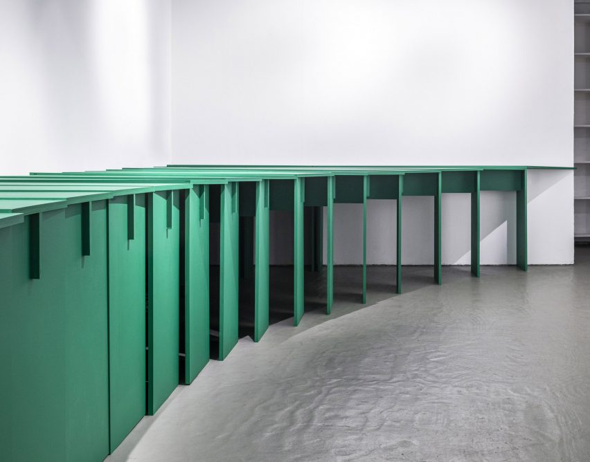 Una fila de mesas verdes entrelazadas diseñadas por Lanza Atelier para escaparates de arte y arquitectura. 